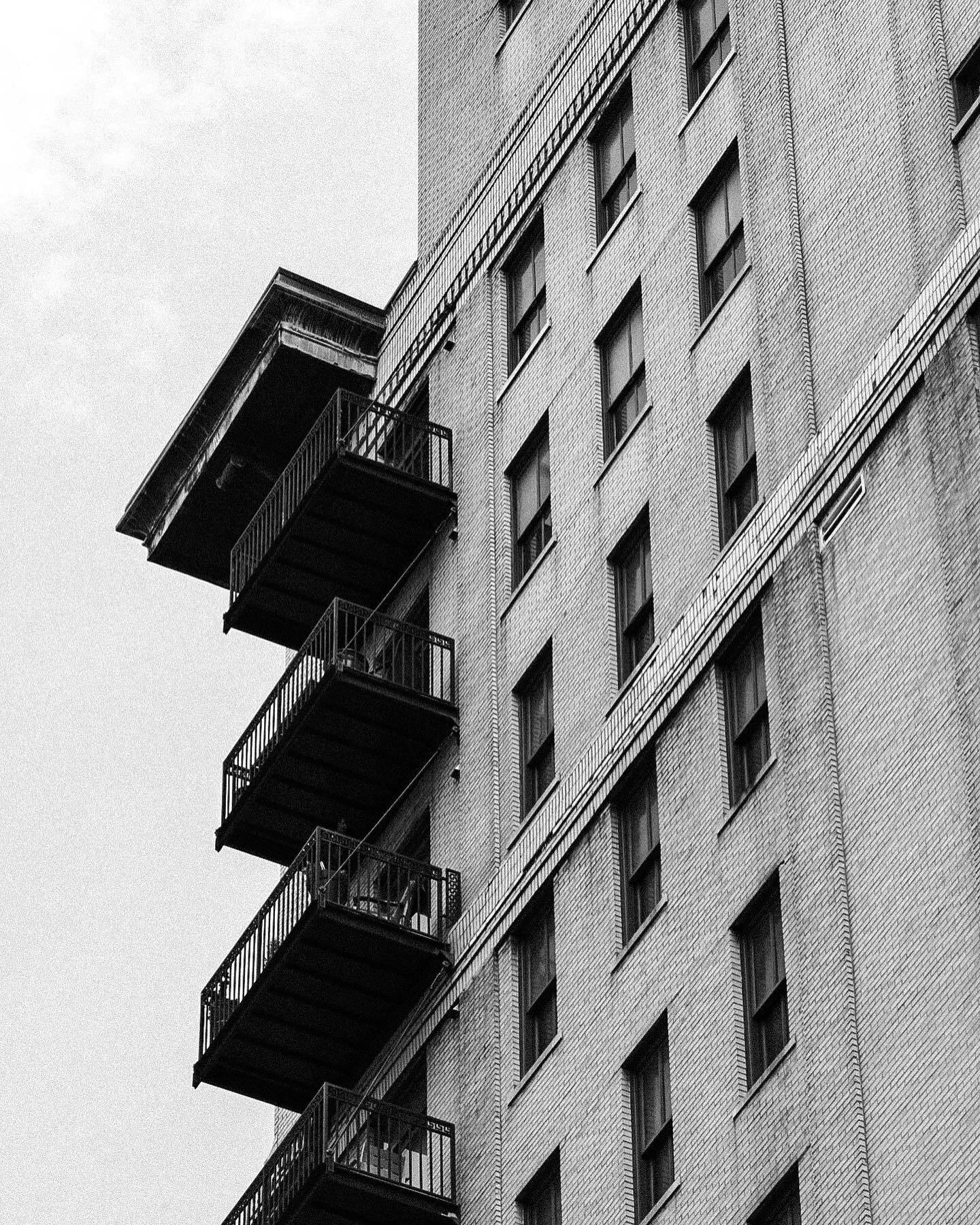 Stacked balconies on a brick building against a white sky