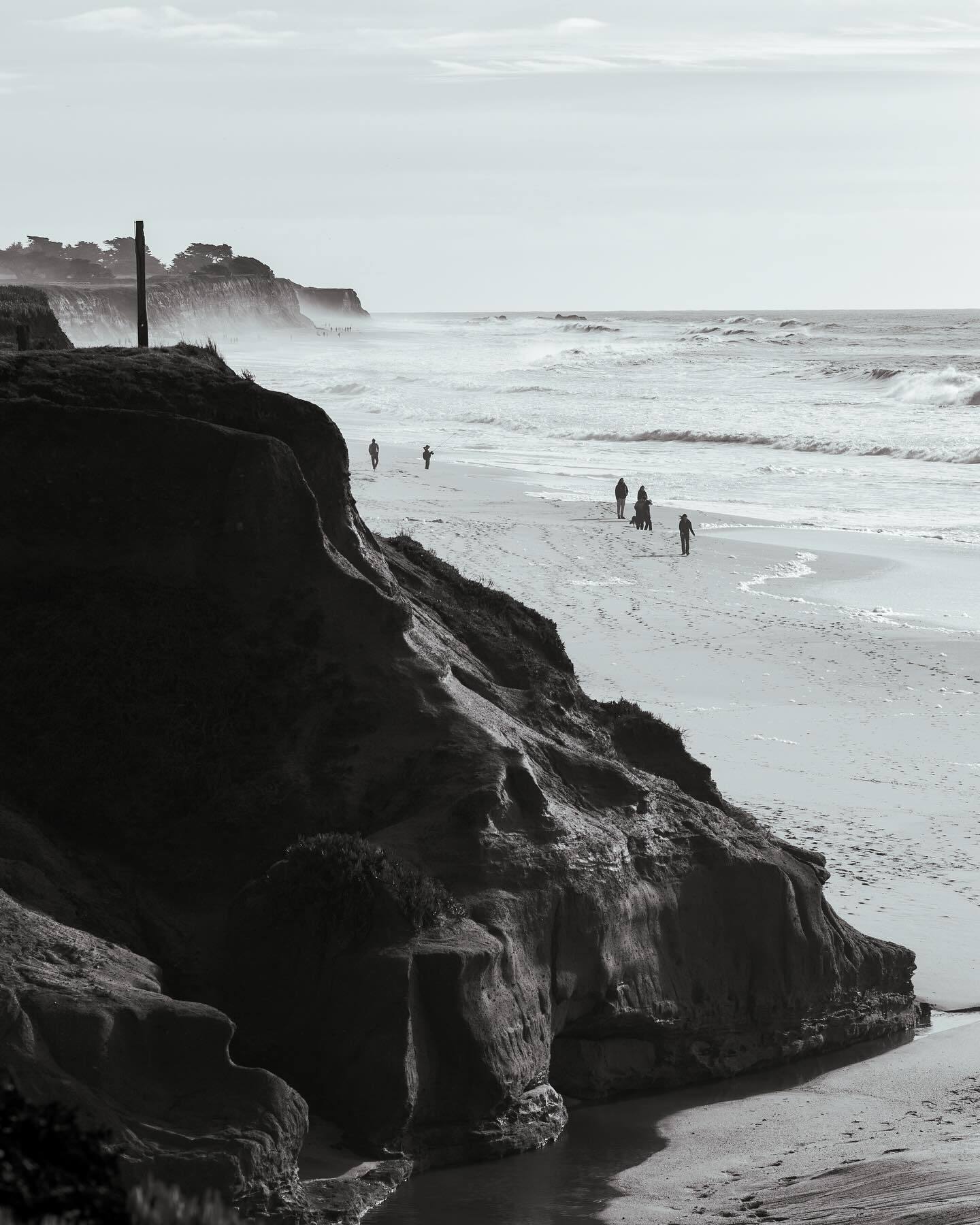 Sandstone cliffs and a long beach under haze, black and white
