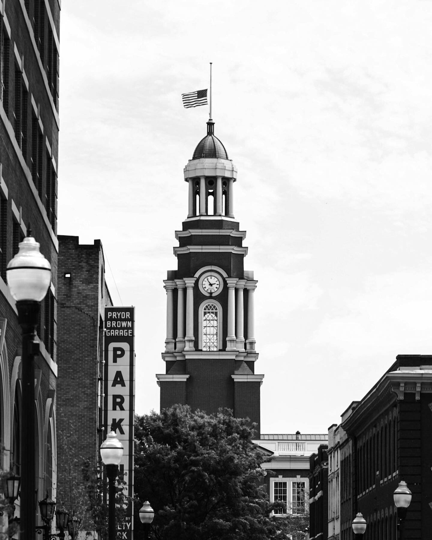 A clock tower and a PARK sign over a downtown street