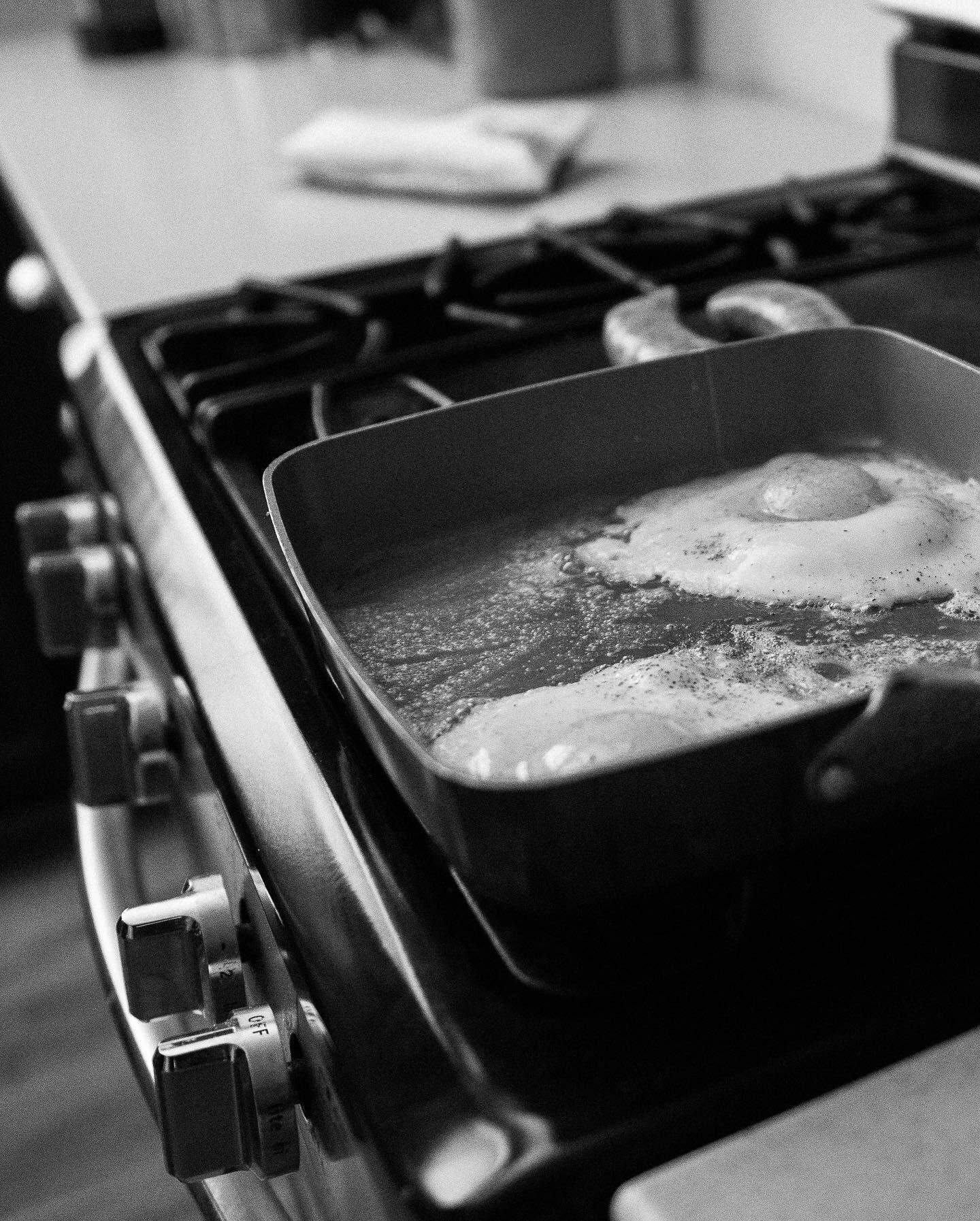 Two eggs frying in a pan on a gas stove