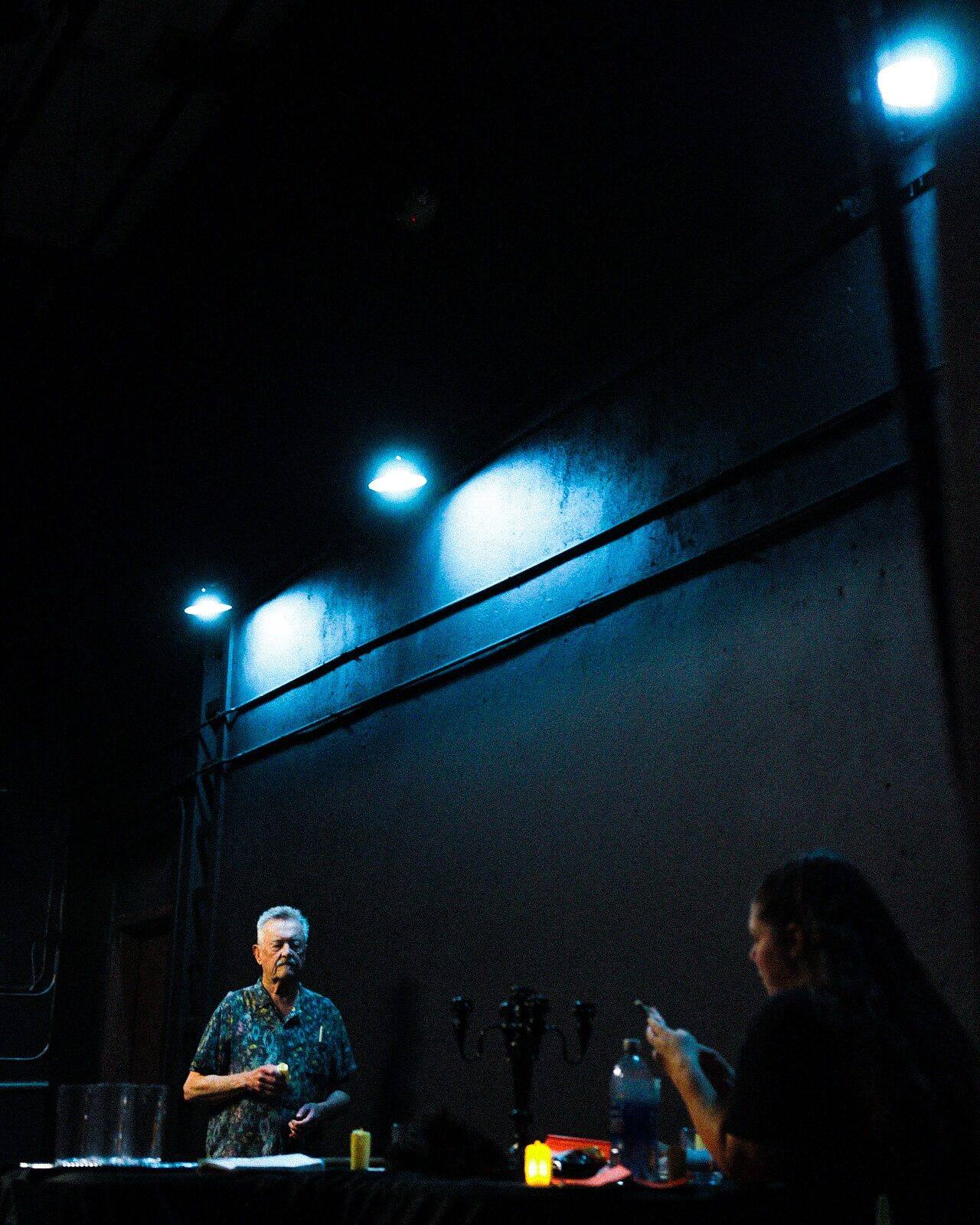 Two people behind a bar in dim blue light
