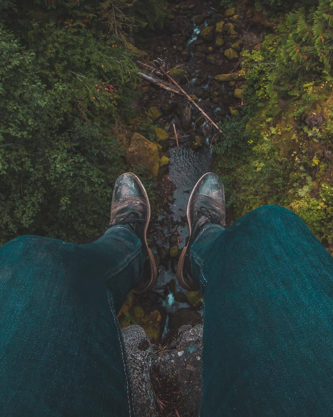 Boots dangling above a forest creek
