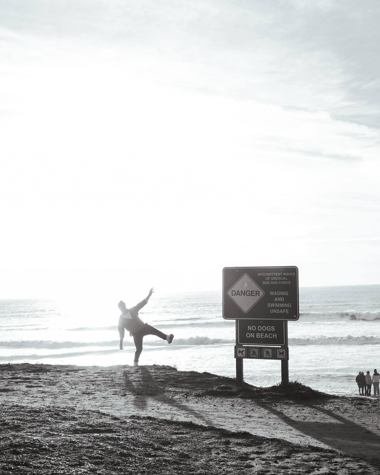 A figure kicks a leg out beside the cliff sign, black and white