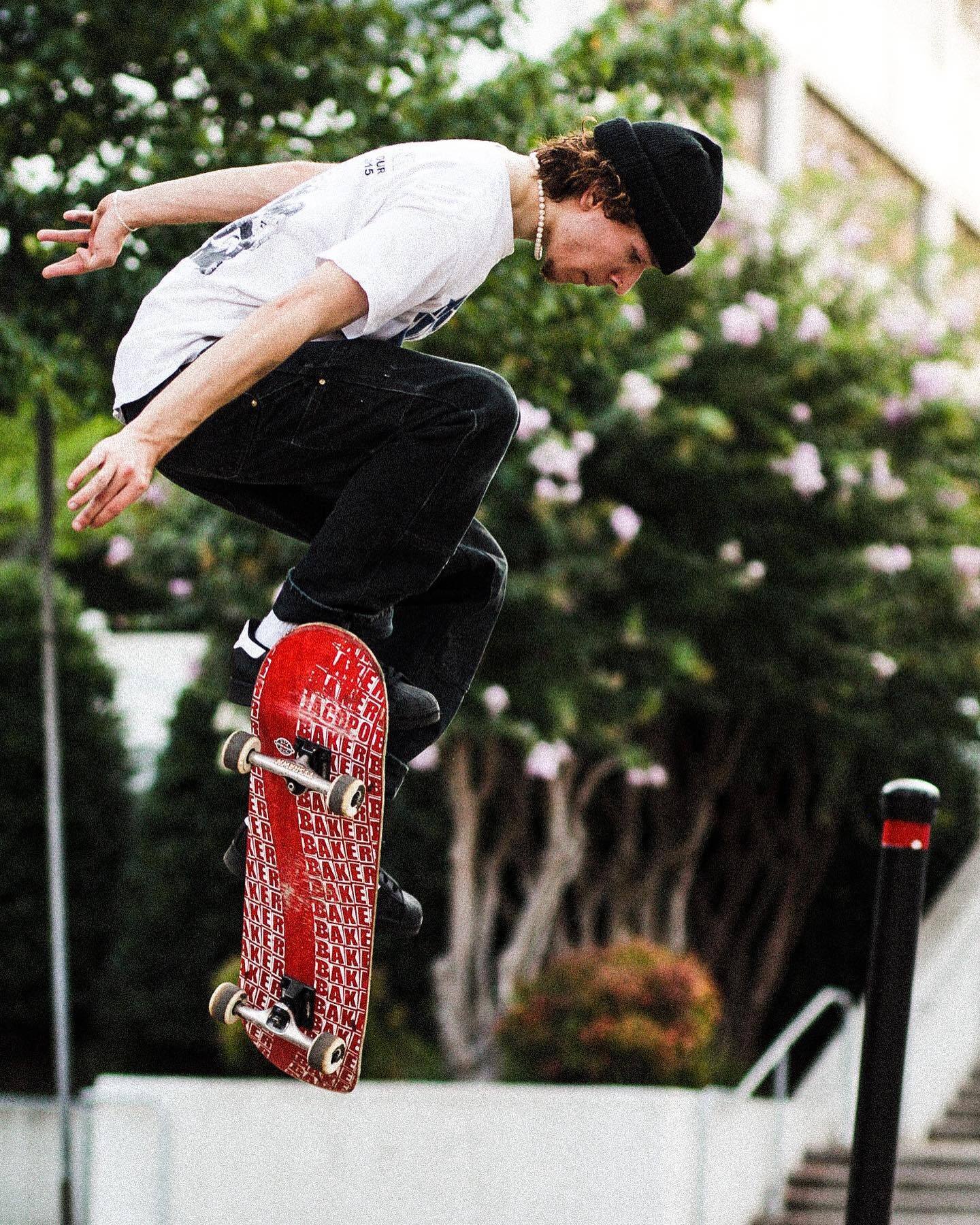 A skateboarder mid-air over a kerb, board flipping beneath him
