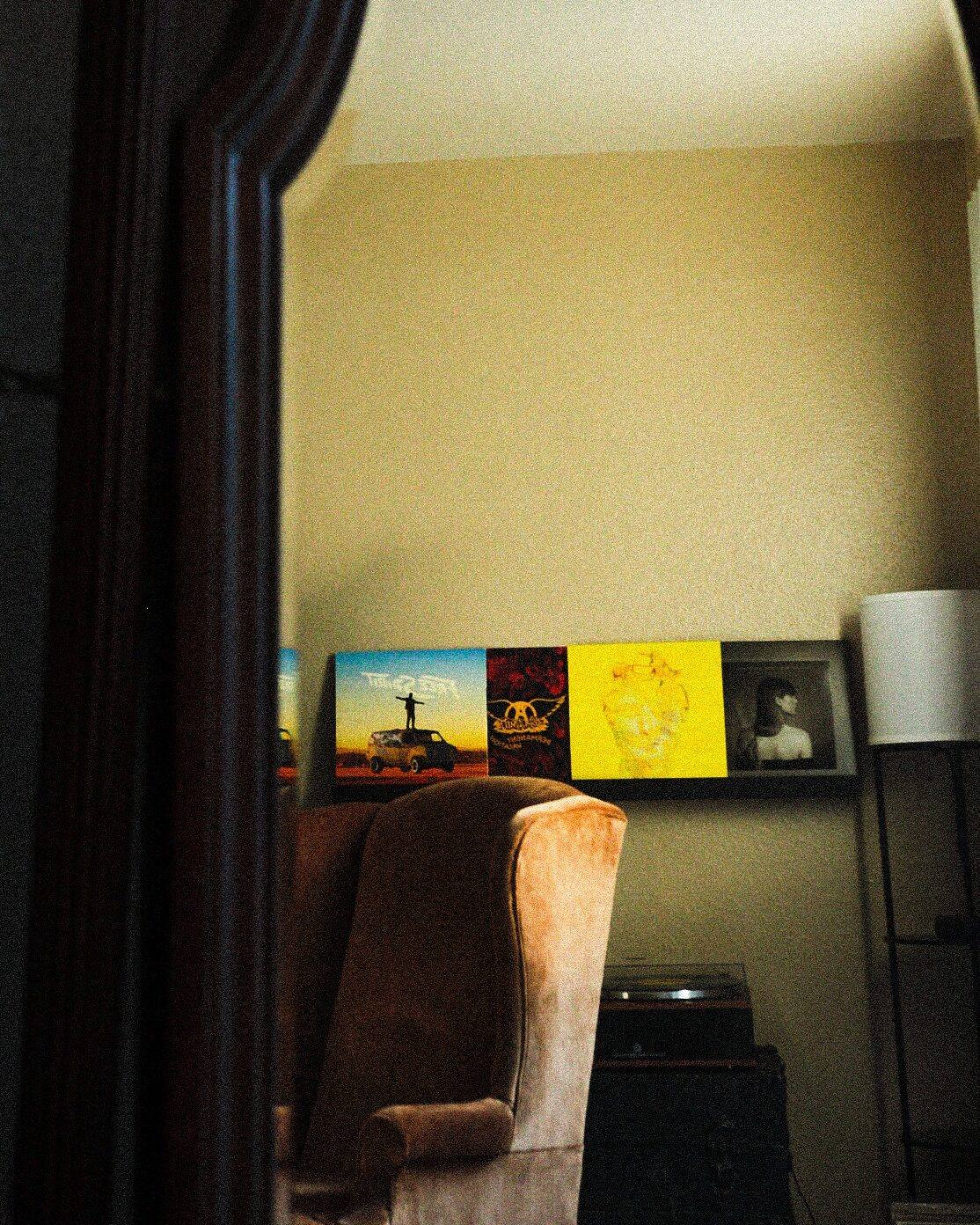 A wingback chair and framed prints seen in a mirror