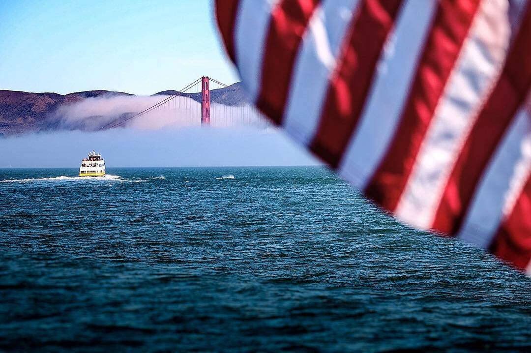 The Golden Gate Bridge in fog behind an American flag